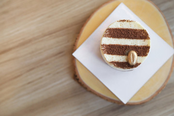 Fototapeta na wymiar Tiramisu cake recipe with golden coffee bean decorated on top on wooden plate.