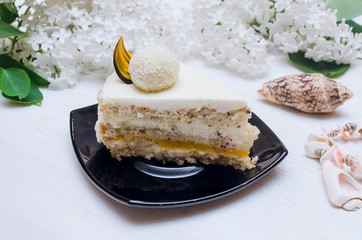 Sponge cake with hazelnut, cheese-coconut cream on natural cream and marmalade layer of passion fruit and white lilac flowers on tree branch.