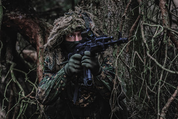 Airsoft player in eastern uniform during playtime in forest