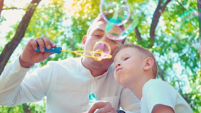 Father with his son blowing soap bubbles, fun family pastime, a child having fun with his dad