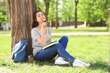 Fototapeta premium Beautiful young woman with notebook resting in park