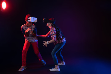 Fototapeta na wymiar Happy day. Joyful cute girl and a boy wearing VR headsets and playing an interesting game