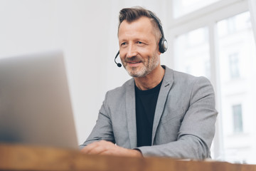 Mature man working with headset in call center