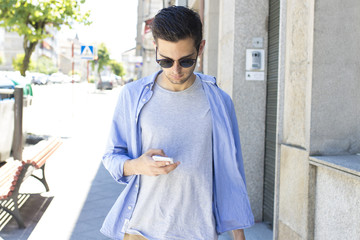 young man with mobile phone walking down the street