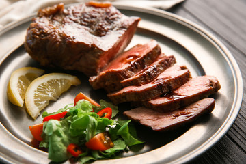 Plate with tasty grilled steak on wooden background, closeup