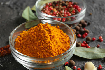 Bowl with turmeric powder and spices on table