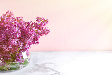 Obraz premium Vase with beautiful blossoming lilac on table against color background