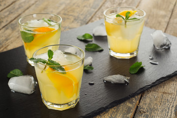 Summer drink. Citrus lemonade with mint and ice on white wooden background.