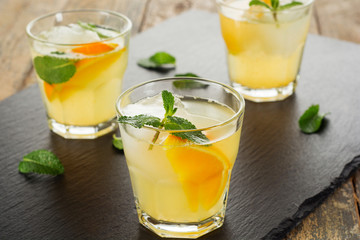 Summer drink. Citrus lemonade with mint and ice on white wooden background.