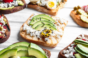 Tasty toasts with avocado on wooden background