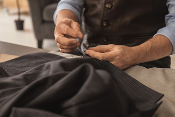 Mature tailor sewing at table in atelier