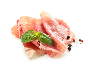 Tasty prosciutto slices with basil and spices on white background