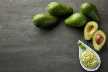 Plate with tasty guacamole and ripe avocados on table