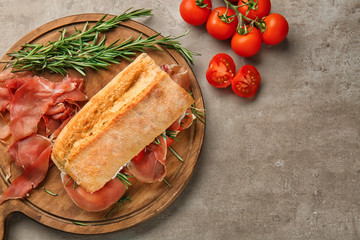 Tasty sandwich with prosciutto on wooden board
