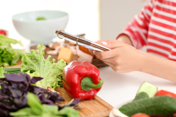 Young woman reading recipe book in kitchen