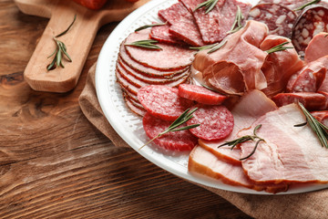 Plate with assortment of delicious deli meats on table
