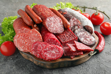 Wooden board with variety of delicious sausages on table