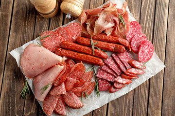 Variety of delicious deli meats on wooden table