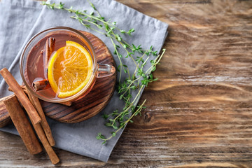 Cup of hot aromatic beverage with cinnamon and orange on wooden board