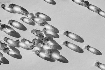 Little glass balls in direct sunlight, macro. Abstract background, black and white photo