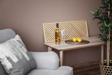 Fototapeta na wymiar Cozy sofa and wooden table with bottle of wine in living room