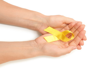 Female hands holding yellow ribbon on white background. Cancer concept