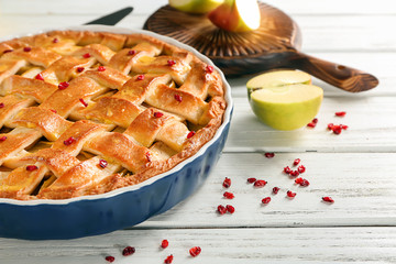 Dish with delicious apple pie on wooden background