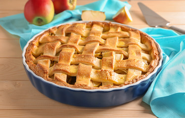 Dish with delicious apple pie on wooden table