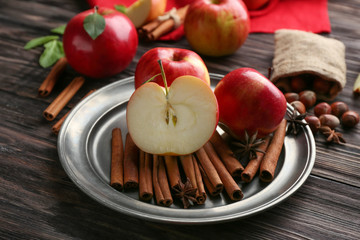 Plate with fresh apples and cinnamon on wooden table