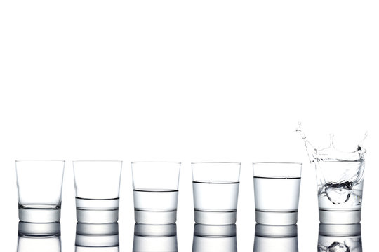 gropu of  glasses filled with different level of water and ice cube spalshing in,  isolated on white background, copy space