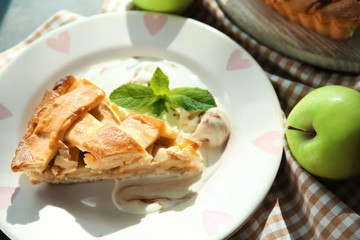 Plate with piece of delicious apple pie on table