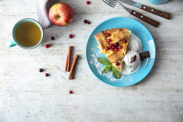 Plate with piece of delicious apple pie and ice cream on wooden background