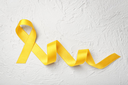 Yellow ribbon on light background. Cancer concept