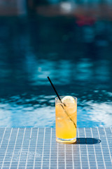 close-up shot of glass of delicious orange cocktail on poolside