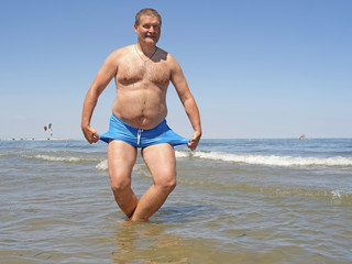 Fototapeta na wymiar comic portrait of the fat man, doing the breast stroke in a water