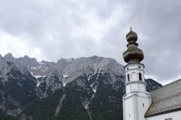 church spire in front of stunning alpine mountain panorama