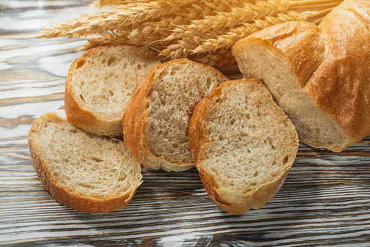 Sliced bread wheat ears on wooden surface