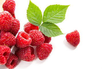 Small plate with ripe raspberries and green leaf isolated on white background.