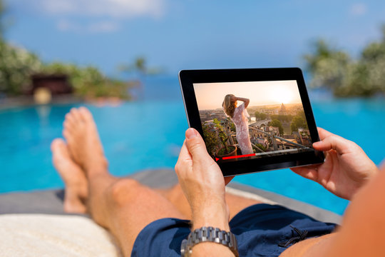 Man Watching Movie On Tablet By The Pool.