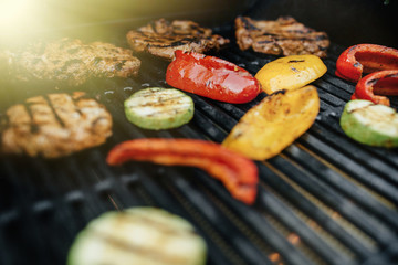 Young man grilling some meat and vegetable on huge grill.