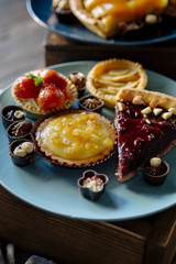 Sweet bar of delicious cakes, candies and pies on a wooden table, decorated with fabric and glass vases. Cute cozy home dinner for a family and friends. Soft window light