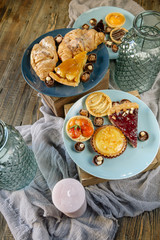 Sweet bar of delicious cakes, candies and pies on a wooden table, decorated with fabric and glass vases. Cute cozy home dinner for a family and friends. Soft window light