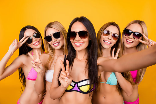 Selfie time, ladies! Five girlfriends in cool swim suits and sunglasses are posing for a selfie photo shot, that brunette is taking. They are gesturing, making memories, enjoying near the pool