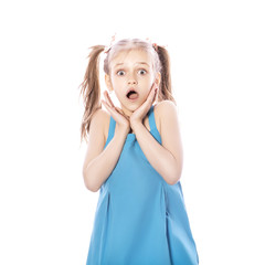 Young seven years old brunette girl in blue dress on a white isolated background. Amazement, surprise emotions on her face