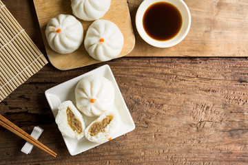 top view of steamed chinese bun (baozi) stuffed with pork chop on old and crack wooden board. popular dim sum food menu.
