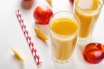 Juice from peaches and nectarines with pulp with fresh fruits on a white background.