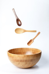 Wooden bowl spoon utensils on white background elevated flying floating