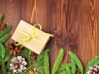 Fototapeta na wymiar Christmas and Happy New Year dark brown background. Gift Christmas box, fir branches, wooden table, top view, copy space