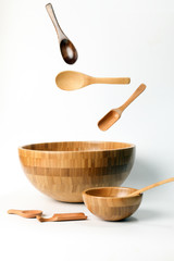 Wooden bowl spoon utensils on white background elevated flying floating