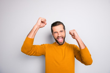 Portrait of cheerful joyful man keeping hands up celebrating achievement isolated on gray background copy-space